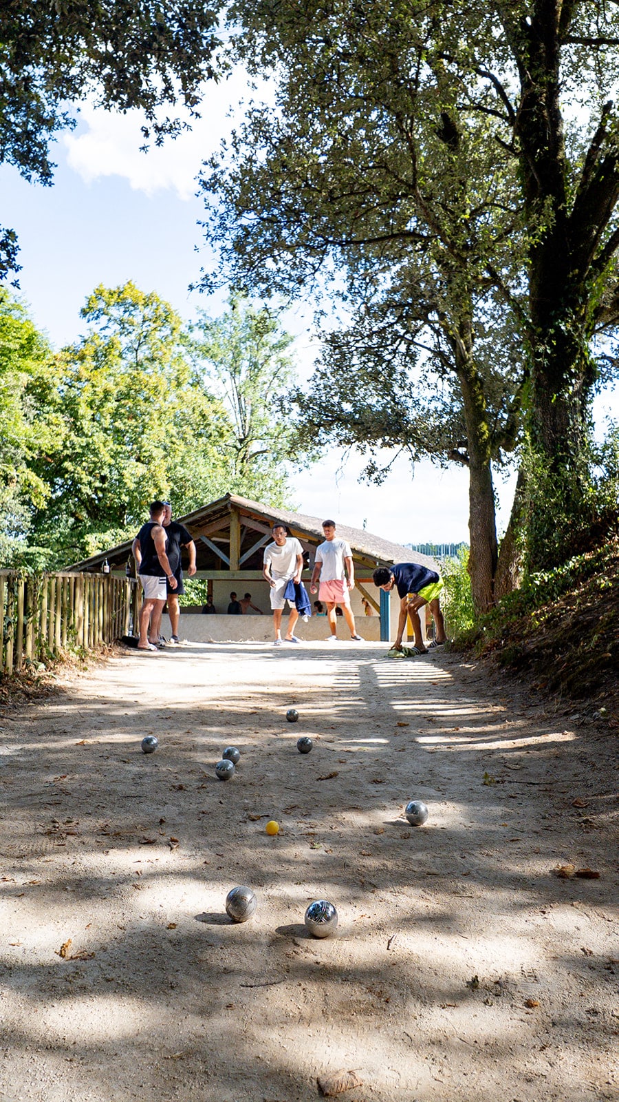 A game of pétanque outdoors under the trees.